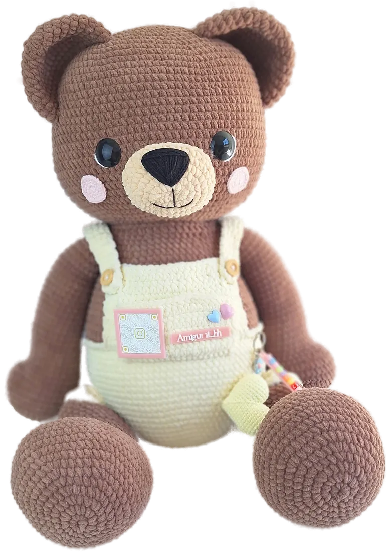 Big Big, o urso gigante de amigurumi em fio pelúcia marrom, com jardineira creme e bochechas rosadas, sentado